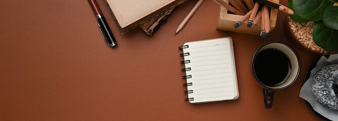 Horizontal image of vintage workplace with coffee cup, notebook, stationery and copy space brown leather.