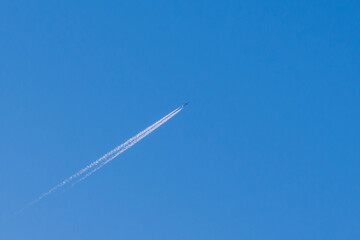 Small Airplane and trail across the blue sky