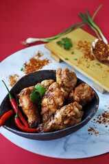 Spicy Chicken Wings in Bowl with Ingredients on Background