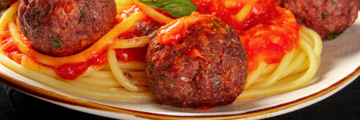 Meatballs with spaghetti close-up panorama, with vibrant tomato sauce