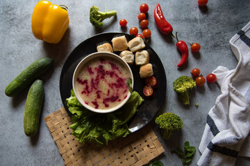 Top view of chicken and red beet soup in a bowl along with bread condiments