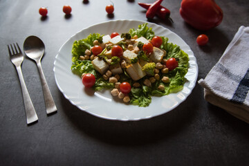 Close up of Chick peas and vegetable salad with cheese in a plate with use of selective focus.