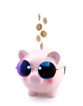 Coins falling into piggy bank on white background