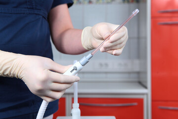 An employee of a dental clinic wipes medical equipment in the surgical room. Disinfection of equipment. An unrecognizable person. A surgical office in a dental clinic. A copy of the space.