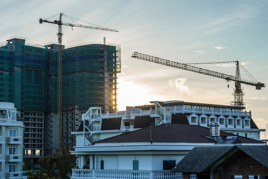 Modern big multi-storey residential or office high rise building under construction, sunrise sky background, tower cranes. Real estate business, buying investing in apartments abroad, mortgage