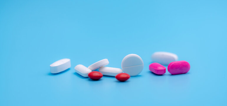 Pharmacy Banner. White And Pink Tablets Pills On Blue Background. Round And Oval Tablets. Painkiller Medicine. Acetaminophen And Ibuprofen Tablets Pills. Pharmaceutical Industry. Painkiller Tablets.