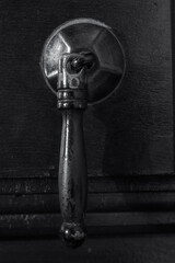 Handle of an antique furniture drawer. Monochrome. Low key. Vertical view.