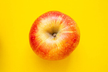 Red apple on a yellow background. Ripe apple top view.