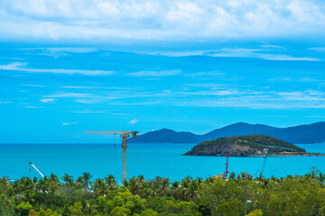 Beauty PANORAMA view. Construction site modern residential district, hotel resort. High tower cranes. Clouds sky, cyan sea, island background, palm forest front view. Real estate invest business