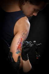 Obraz na płótnie Canvas Female tattoo artist making tattoo on a men’s arm