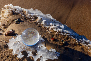 Glass ball stands at sea in the sand of Jurmala