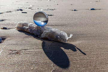 Obraz premium Glass ball stands at sea in the sand of Jurmala