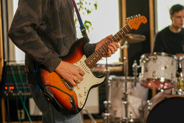 The guy plays the electric guitar to record the sound. He holds a guitar in his hands - obrazy, fototapety, plakaty