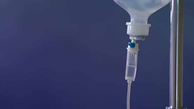 Close up. Saline solution for patient in hospital. IV drip, NSS Intravenous on blue background in operation room.