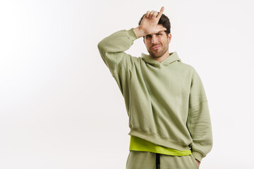 Happy handsome man in sportswear smiling and pointing finger upward
