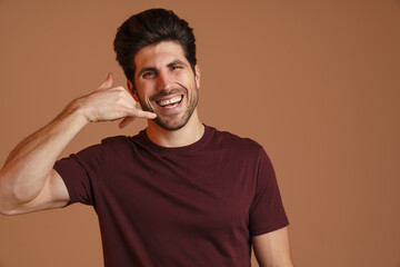 Happy masculine man smiling while showing handset gesture