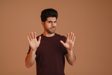 Displeased unshaven young man showing stop gesture at camera