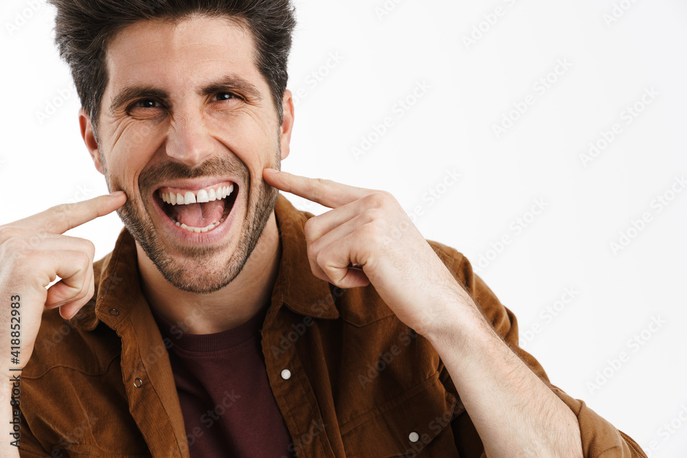 Wall mural Happy handsome man smiling and pointing fingers at his cheeks