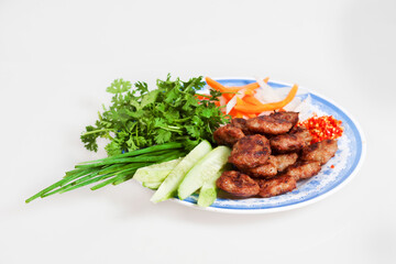 Grilled pork on the dish isolated on white. Famous Vietnamese food is banh mi thit, fresh herbs as scallions, coriander, carrot, cucumber, chilli.