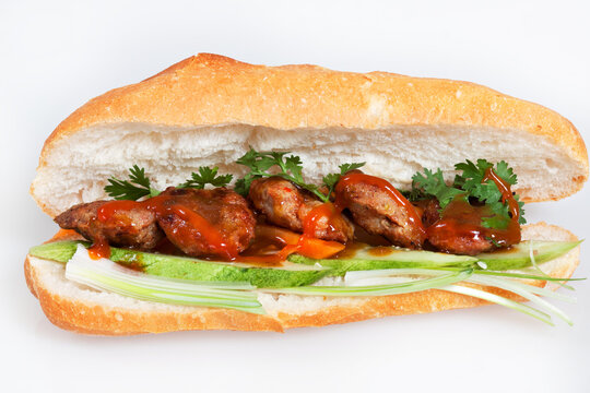 Famous Vietnamese food is banh mi thit, popular street food from bread stuffed with raw material: grilled pork and fresh herbs as scallions, coriander, carrot, cucumber, chilli. On White