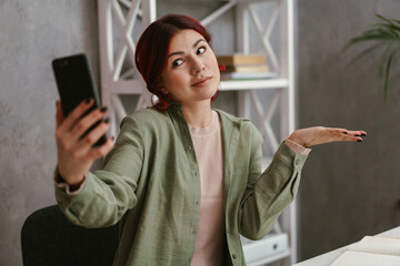 Confused woman holding copyspace while taking selfie photo on mobile phone