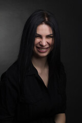 Studio portrait of a brunette in black clothes on a dark background
