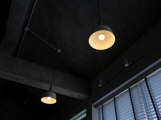 Modern round ceiling light with light bulb hanging from concrete construction.