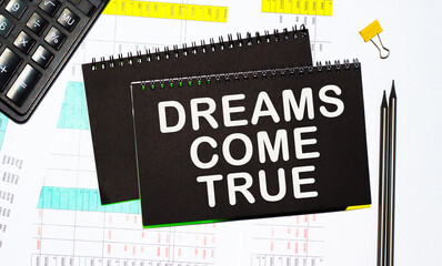 text DREAMS COME TRUE Written words on paper notebook . workplace. Business concept.