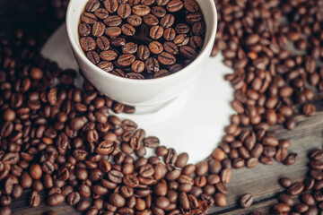 coffee beans on a wooden background and a cup on a saucer close-up macro photography