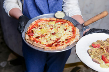 Gourmet pizza with barbeque sauce, grilled chicken, cheese served by waiter in restaurant or diner.