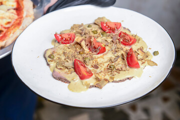 Assorted meats, delicious sauce and tomatoes served by waiter in restaurant or diner.