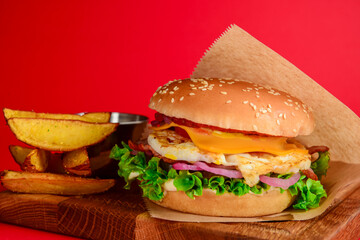 Bacon and chicken burger with red onions and cheese over red background. Fast food, junk food concept.