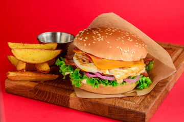 Bacon and chicken burger with red onions and cheese over red background. Fast food, junk food concept.