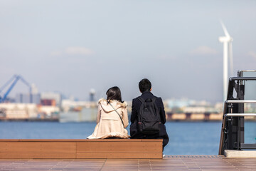 港の公園のベンチに座って海を見る恋人たち