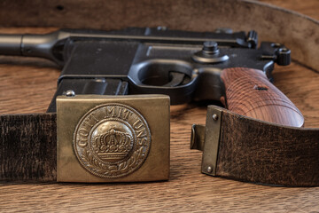 Obraz premium Deutsches Koppel aus dem 1. Weltkrieg (1914-1918) auf rustikalem alten Holz, im Hintergrund eine alte Mauser Pistole