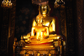 Two golden meditating Buddha statues in a Thai temple