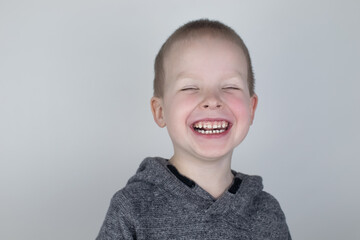 Close-up of a blond boy who smiles into the frame. White milk teeth. Perfect smile. The concept of...