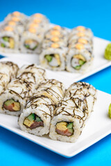 Sushi large set served on a white plate over blue background. Traditional Asian Japanese cuisine concept.