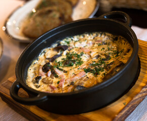 fried pieces of meat with vegetables and bechamel sauce baked in cast iron skillet