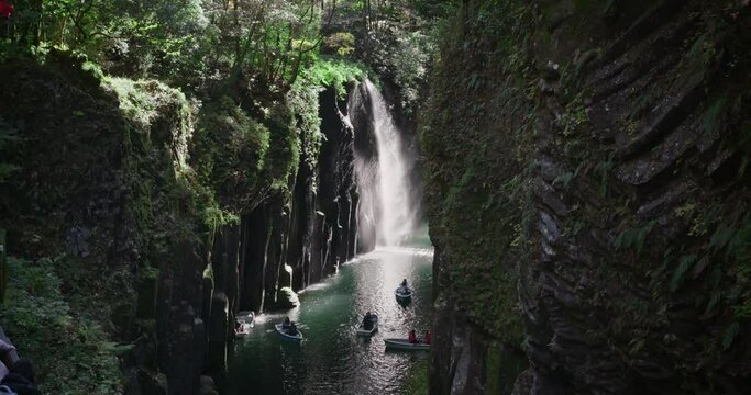 Waterfall in the mountains at Takachiho gorge, Miyazaki, Japan. Rowing a boat in a volcanic canyon near one of the most beautiful waterfall in Japan.