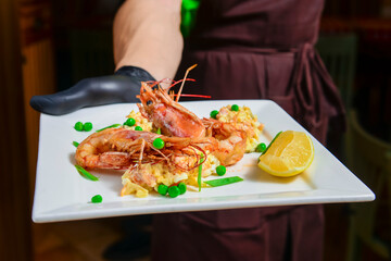 Shrimps, avocado and salmon salad served on a white plate by waiter in restaurant or diner.