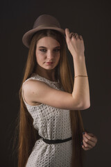 Girl in a delicate white dress and a beige hat with narrow brim