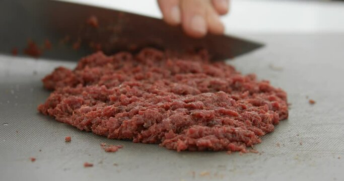Horse meat finely chopped using sharp knife, preparing Steak Tartare, or minced steak, close-up