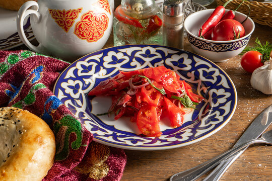 Vegetable salad of tomatoes and onions in a plate with an Uzbek pattern