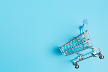 Shopaholic. Buyer. Shopping concept. Close-up. Isolated shopping trolley on a blue  background. Copy space.