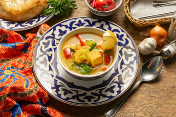 Fish soup of salmon and vegetables in a plate with traditional Uzbek ornaments