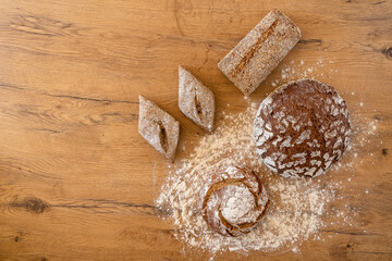 Different loafs of bread on a wooden table surrounded by flour.  Concept for a bakery or baking bread in the kitchen.