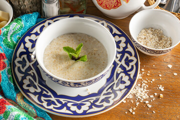 Classic oatmeal porridge with milk decorated with mint leaves