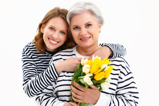 Happy senior woman with bunch of tulips smiling in studio with young daughter