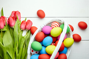 Easter Eggs in basket and spring flowers on white wooden table